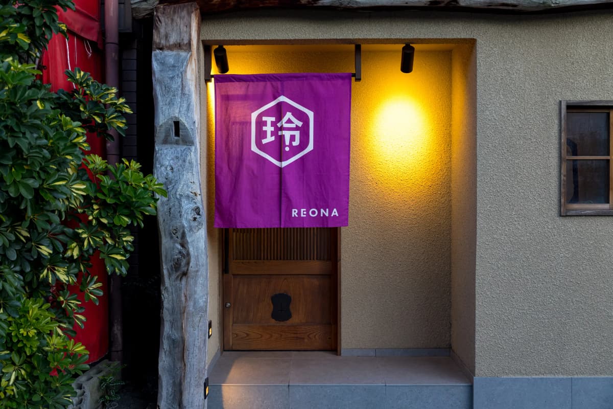 REONA Sushi Tokyo is marked by a vibrant Noren (curtain) in the quiet, historic area of Kanda.