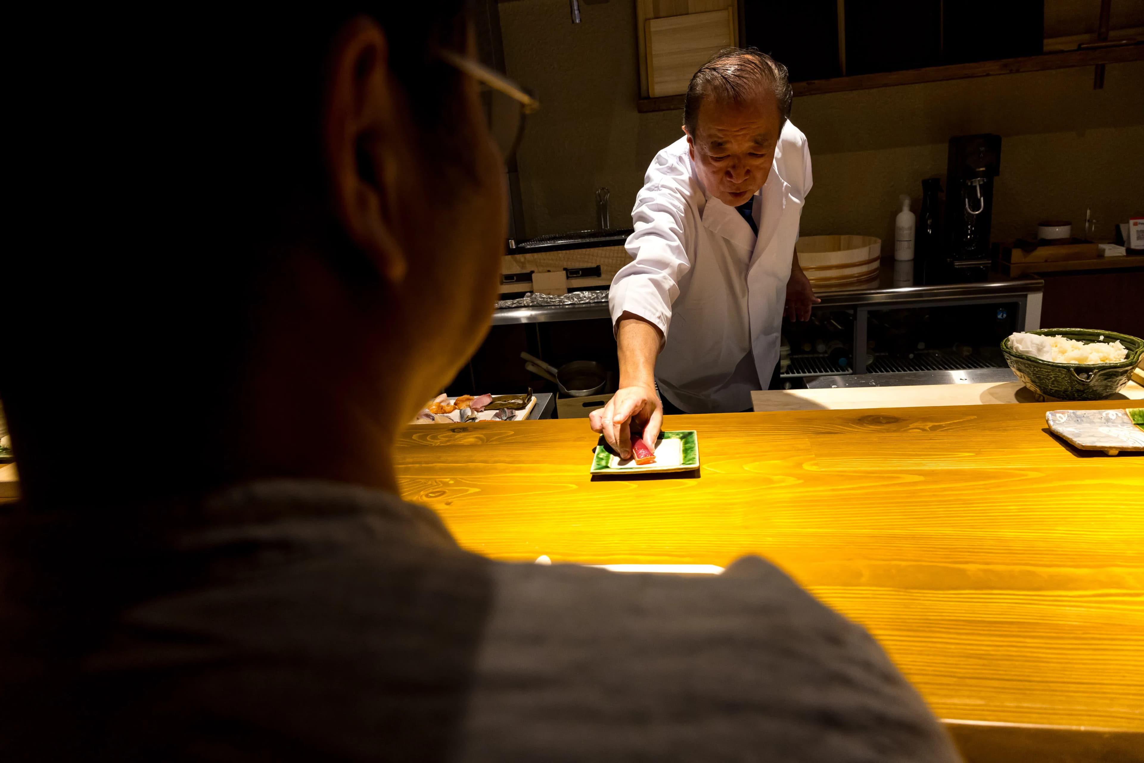 Sushi chef serving premium tuna nigiri at the counter